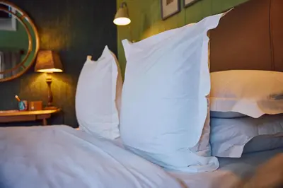 a bed with white pillows on top of it at The Sun Inn in Dedham