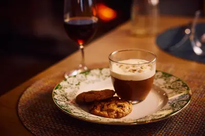 a plate with a drink and cookies on a table at The Sun Inn in Dedham