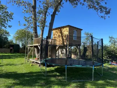 a playground with a tree house in the grass at The Bus Stop, Thornham Magna in Thornham Magna