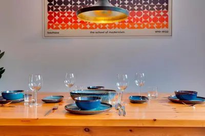 a wooden table with plates and wine glasses on it at Modern and Stylish Townhouse in City Centre Pass the Keys in Cambridge