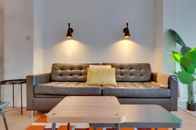 a living room with a leather couch and a table at Modern and Stylish Townhouse in City Centre Pass the Keys in Cambridge