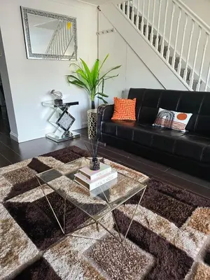a living room with a black couch and a glass table at Relaxed Leigh-on-Sea Escape, Family-Friendly & Contractor Stays in Hockley