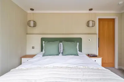 a bedroom with a large bed with two green pillows at Finest Retreats - Cambridge Luxury Lodge