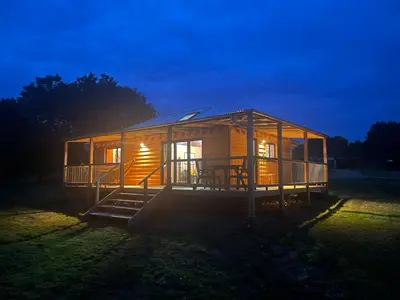 a wooden cabin in a field at night at Okovango Cabin in Holton