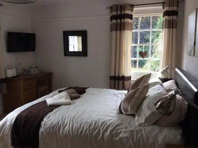 a bedroom with a bed with white sheets and a window at Beightons Bed and Breakfast in Bury Saint Edmunds