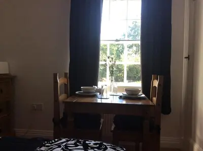 a wooden table with two chairs and a window at Beightons Bed and Breakfast in Bury Saint Edmunds