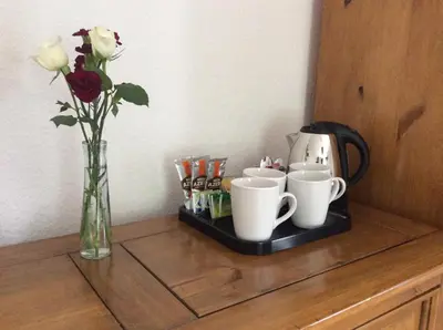 a table with a vase of flowers and coffee cups at Beightons Bed and Breakfast in Bury Saint Edmunds
