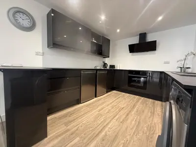 a kitchen with black cabinets and a clock on the wall at Stylish 3 bed spacious flat in Brentwood
