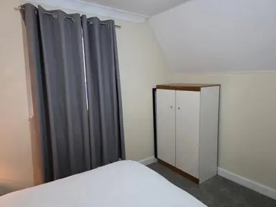 a bedroom with gray curtains and a bed and a cabinet at Stay Near Colchester twn centre4 in Colchester