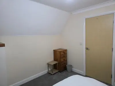 a bedroom with a bed and a dresser and a door at Stay Near Colchester twn centre4 in Colchester