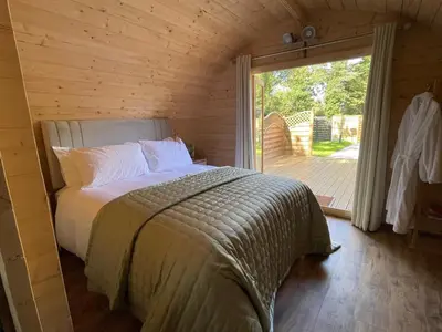 a bedroom with a bed in a room with a large window at Highgate Cabin in Takeley