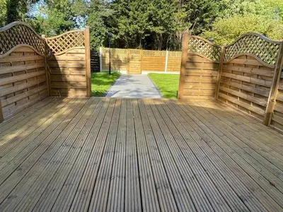 a wooden deck with a gate and a driveway at Highgate Cabin in Takeley