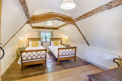 two beds in a attic bedroom with white walls and wooden floors at 4 Bed in St. Nicholas South Elmham oc-o32397 in Saint Margaret