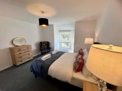 a bedroom with a bed and a dresser and a window at Lime Tree in blue House in Cambridge