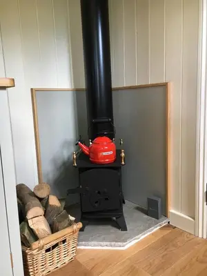 a wood stove with a red pot on top of it at The Scrumpy Shepherd, Brandeston in Blundeston