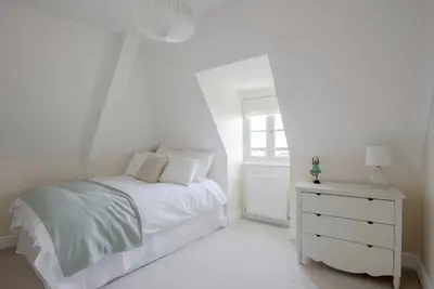 a white bedroom with a bed and a dresser at Amazing Abodes in Chelmsford