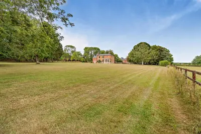 a large field with a house in the background at 6 Bed in Cowlinge oc-b32762 in Cowlinge