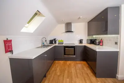a kitchen with gray cabinets and a wooden floor at Newly Renovated Sanctuary for 4 in Charlotte House in Ipswich
