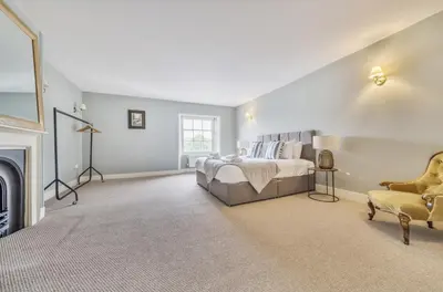 a large bedroom with a bed and a fireplace at 6 Angel Hill, Bury st Edmunds in Bury Saint Edmunds