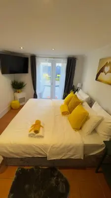 a bedroom with a large white bed with yellow pillows at Peaceful Springfield Studio in Chelmsford