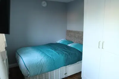 a small bedroom with a bed with blue sheets at Galleywood House in Great Baddow