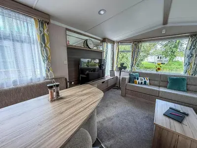 a living room with a couch and a wooden table at Cosy 8 Berth Caravan With Decking And Lake-Views At Weeley Bridge Ref 69001Lv in Clacton-on-Sea
