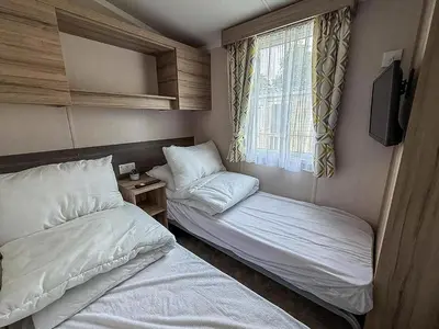 a small room with two beds and a window at Cosy 8 Berth Caravan With Decking And Lake-Views At Weeley Bridge Ref 69001Lv in Clacton-on-Sea