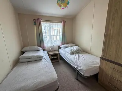 two beds in a small room with a window at Stunning Lodge With Full Sea Views At Coopers Beach Holiday Park Ref 49019S in East Mersea