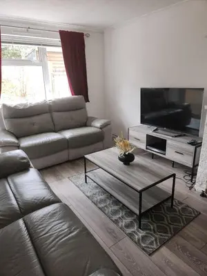 a living room with a leather couch and a flat screen tv at Beautiful two Bedroom house Entire house in Stevenage