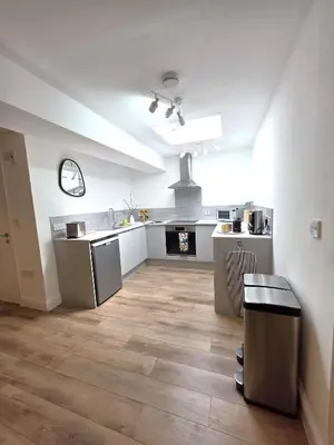 a kitchen with white counters and a wooden floor at Deluxe One Bed Flat at Dawe Luxury Suites - An Entire Apartment near Ely Cathedral & Train Station - Ideal Gateway to Explore Ely, Cambridge, Norfolk & London - Sleeps up to 4 in Ely