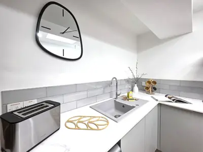 a white kitchen with a sink and a mirror at Deluxe One Bed Flat at Dawe Luxury Suites - An Entire Apartment near Ely Cathedral & Train Station - Ideal Gateway to Explore Ely, Cambridge, Norfolk & London - Sleeps up to 4 in Ely