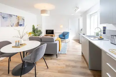 a kitchen and living room with a couch and a table at Cozy One Bed Flat at Dawe Luxury Suites - An Entire Apartment near Ely Cathedral & Train Station - The Perfect Base to Explore Ely, Cambridge, Norfolk & London - 2 Guests Max & Pet Friendly in Ely