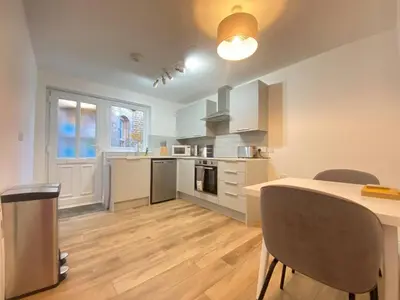 a kitchen with white cabinets and a table and chairs at Stunning One Bed Flat at Dawe Luxury Suites - An Entire Apartment near Ely Cathedral & Train Station - The Perfect Base to Explore Ely, Cambridge, Norfolk & London - 2 Guests Max in Ely