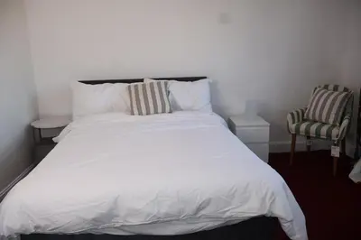 a white bed with two chairs in a bedroom at Homely three bedroom in Vange