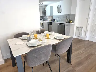 a dining room table with chairs and a kitchen at Modern One Bed Flat at Dawe Luxury Suites - An Entire Apartment near Ely Cathedral & Train Station - The Perfect Gateway to Explore Ely, Cambridge, Norfolk & London - Sleeps up to 4 in Ely