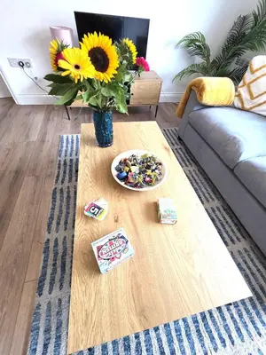 a table with a vase of sunflowers in a living room at Modern One Bed Flat at Dawe Luxury Suites - An Entire Apartment near Ely Cathedral & Train Station - The Perfect Gateway to Explore Ely, Cambridge, Norfolk & London - Sleeps up to 4 in Ely