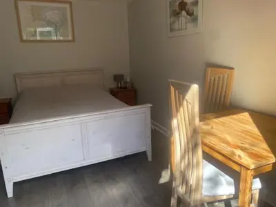 a bedroom with a white bed and a wooden table at Latchmead in Little Hallingbury