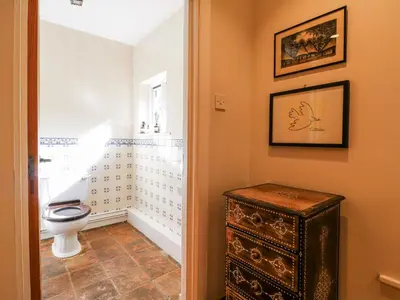 a bathroom with a toilet and a wooden cabinet at Headland Barn in Maldon