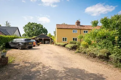 a driveway in front of a yellow house at Farm View Cabin, Kelsale in Kelsale