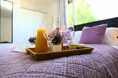 a tray with wine glasses and other items on a bed at Hertfordshire - Stylish 6BR Retreat, 3 Parking in Stevenage