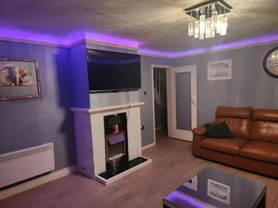 a living room with a fireplace with a flat screen tv at Stacey's Cozy Home in Basildon