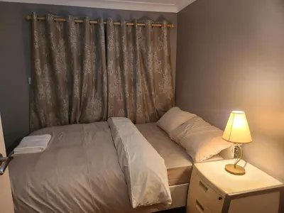 a bedroom with a bed with a curtain and a lamp at Stacey's Cozy Home in Basildon