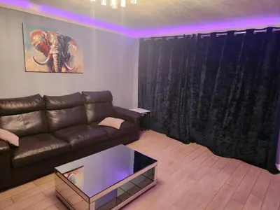 a living room with a leather couch and an elephant painting at Stacey's Cozy Home in Basildon