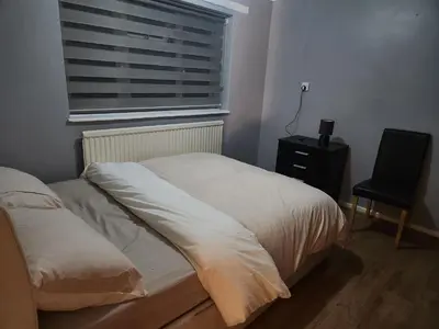 a bedroom with a bed and a window and a chair at Stacey's Cozy Home in Basildon
