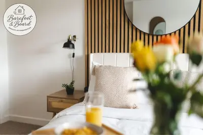 a bedroom with a bed and a table with a vase of flowers at Luxury 2-Bed House in Stevenage Sleeps 6 Free Parking Barefoot & Board in Shephall