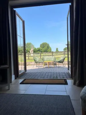 an open door to a patio with a table and chairs at Cottage nestled in the heart of a stunning Suffolk Village in Chediston