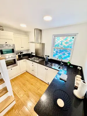 a kitchen with white cabinets and a black counter top at Beautiful Modern 2 Bed house combined with a vintage feel near Central Cambridge Sleeps 4 in Cambridge