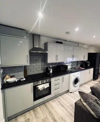 a kitchen with white cabinets and a washer and dryer at One bed flat in Sunny Southend! in Southend