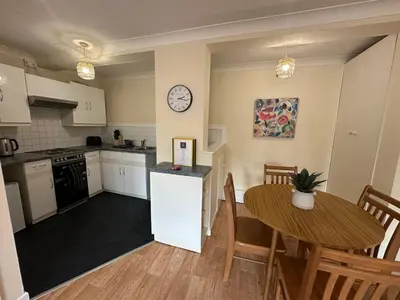 a kitchen with a table and a clock on the wall at Ely Stays Flat 2 in Ely
