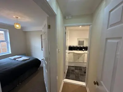 a bedroom with a bed and a small bathroom at Ely Stays Flat 2 in Ely